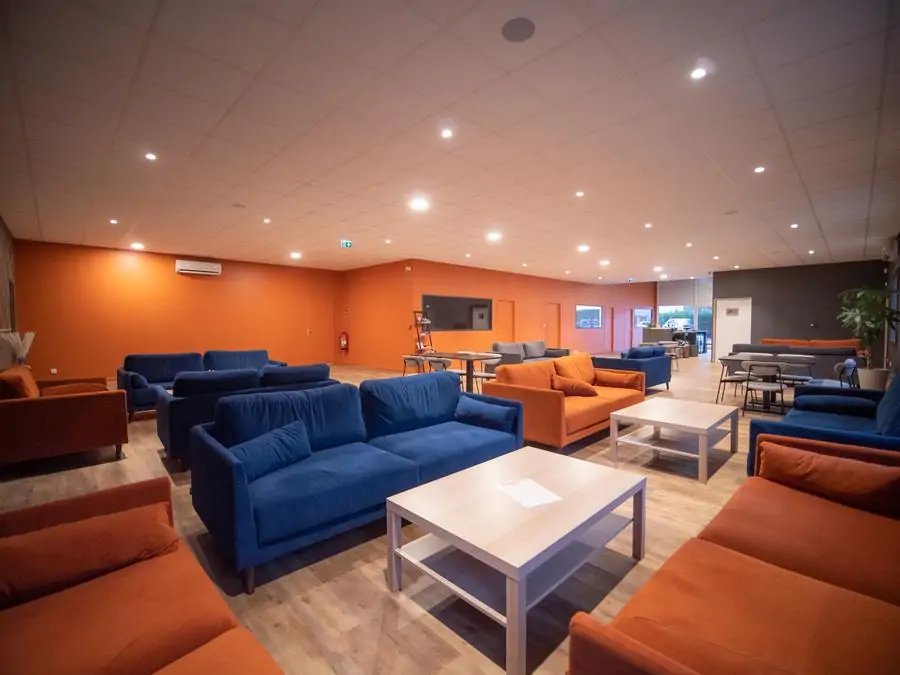 Espace bar convivial d'Oxmoz VR avec canapés bleus et orange à Blagnac
