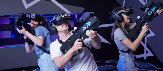 Trois joueurs équipés de casques VR et de blasters dans la zone Arena d'Oxmoz VR à Blagnac